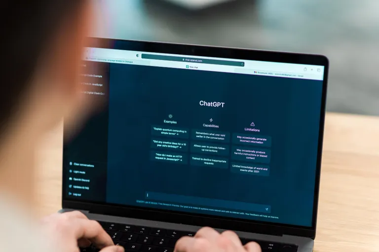 Person types on a laptop displaying the ChatGPT interface at a desk.
